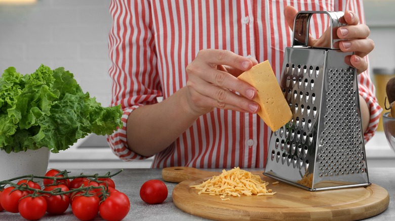 Person grating cheese with box grater