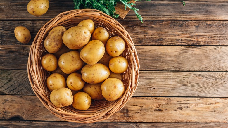 Basket of clean potatoes on wooden table