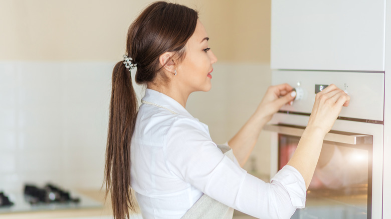 A woman turning on the oven