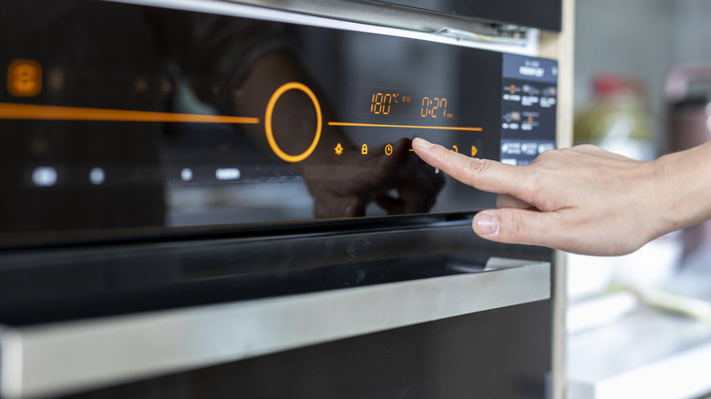 A person setting the oven temperature