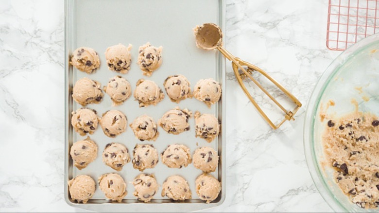 An overcrowded baking sheet with cookie dough