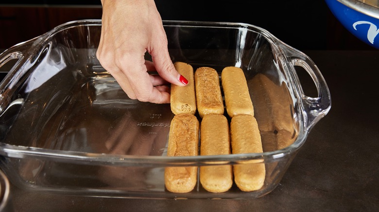 Ladyfingers being placed in baking dish