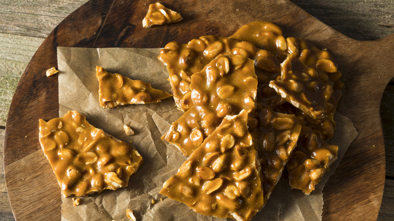 Wooden board with peanut brittle on top.