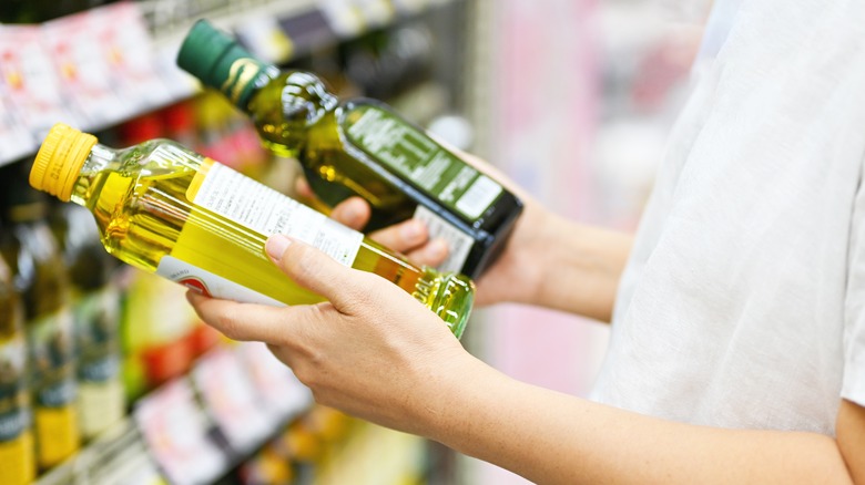 Person holding two bottles of oil