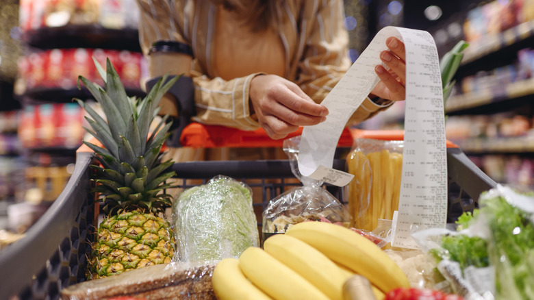 woman looking at long grocery receipt