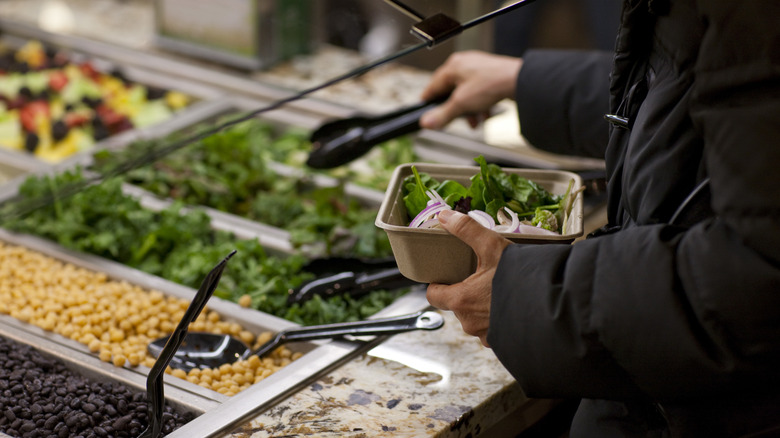 person getting food at whole foods salad bar