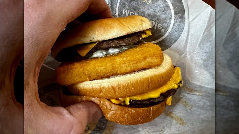 Hand holding a McDonald's Surf & Turf burger, made of a Filet-O-Fish and a Double Cheeseburger