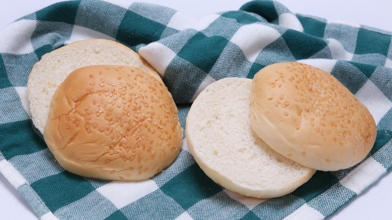 Sliced sesame seed buns on checkered tablecloth