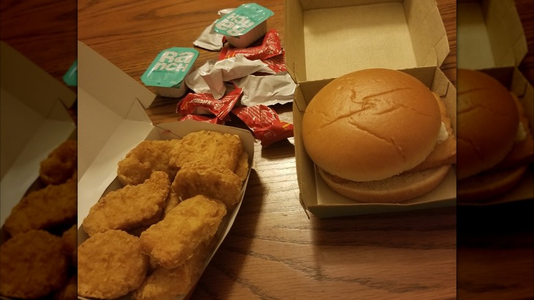 Box of Chicken McNuggets sitting next to Filet-O-Fish, with sauces and dips