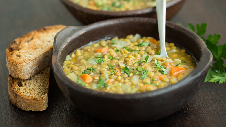 Lentil soup with vegetables in small block bowl, with toasted bread on the side.