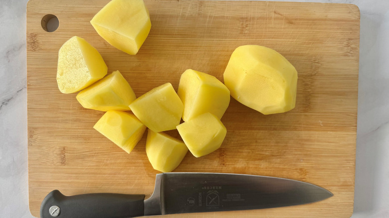 Chopped potatoes on a wooden board with a knife