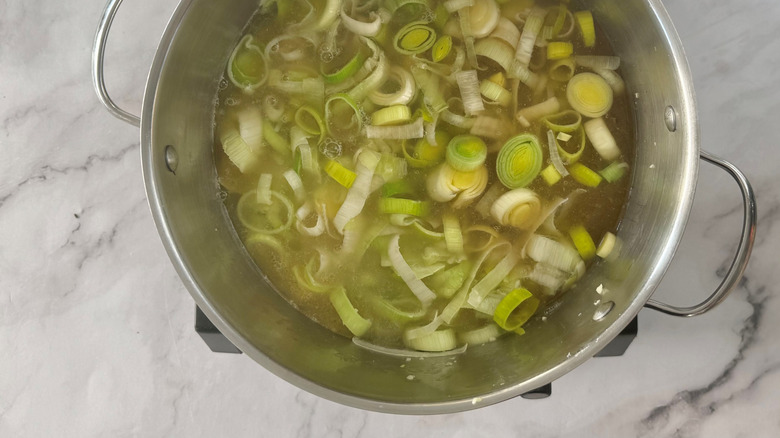 Chopped leeks in a metal pot full of liquid