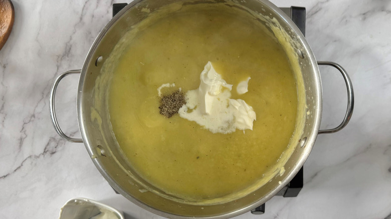 Sour cream floating in a metal pot full of yellow liquid