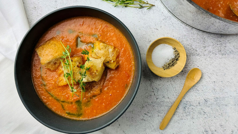 tomato soup with croutons in a black bowl