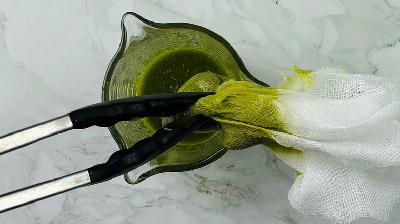 tongs squeezing a piece of cheesecloth