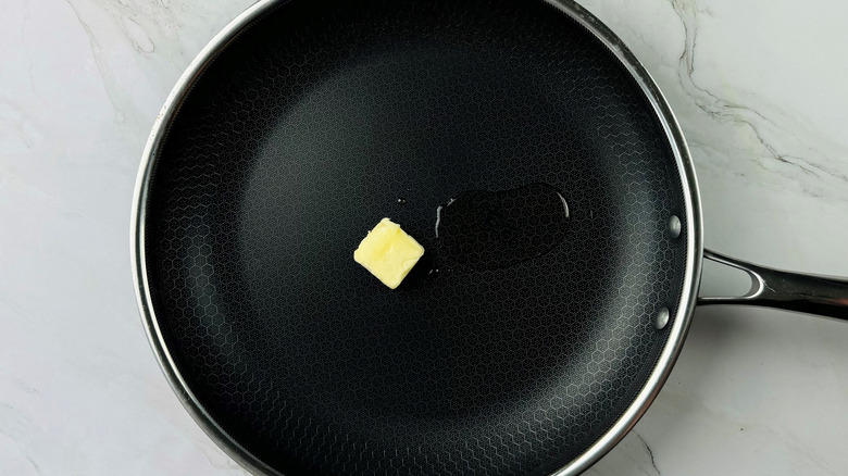 Chunk of butter and puddle of oil in a black frying pan