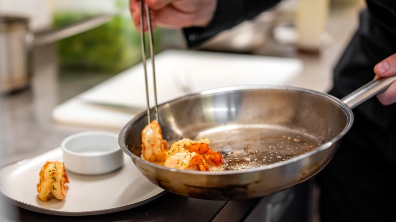 Chef taking shrimp out of pan with tongs