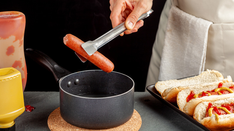 A cook boiling hot dogs