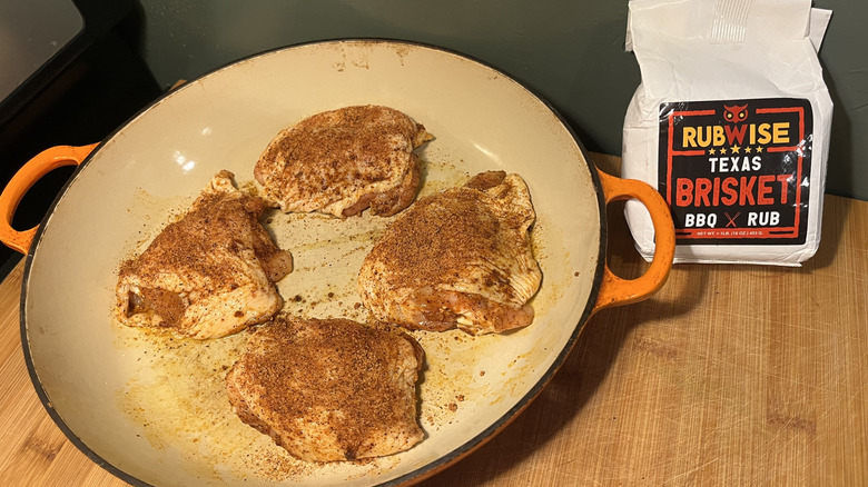 Four chicken thighs covered in seasoning in a pan