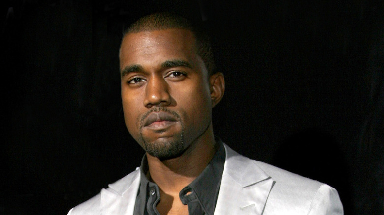 Kanye West in black shirt and white jacket, unsmiling