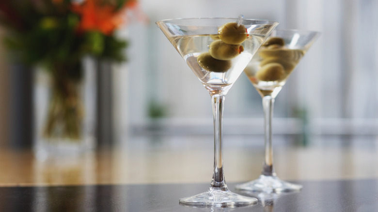 Two dirty martinis in a glass with olives