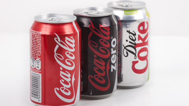 A can of Coca-Cola, a can of Coca-Cola Zero, and a can of Diet Coke