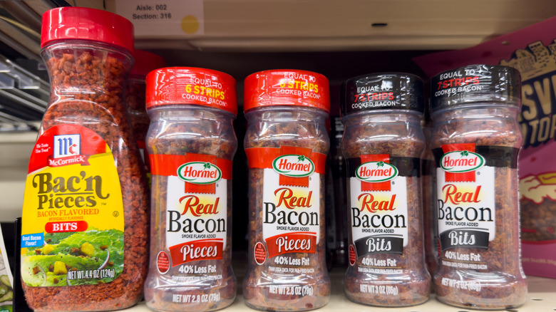 Different containers of bacon bits on shelf.