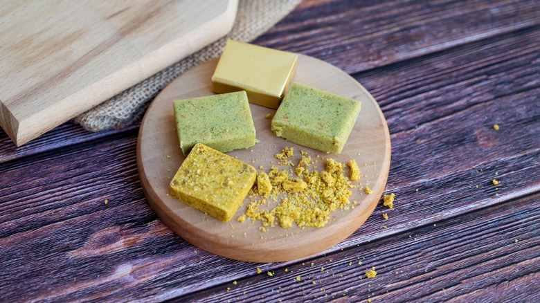 Different colored bouillon cubes on wooden board