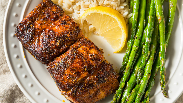 Blackened fish served with asparagus, rice, and a lemon wedge