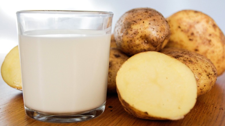 Glass of milk next to potatoes on wood table