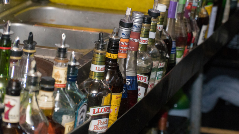 Liquor bottles lined up on a speed rail