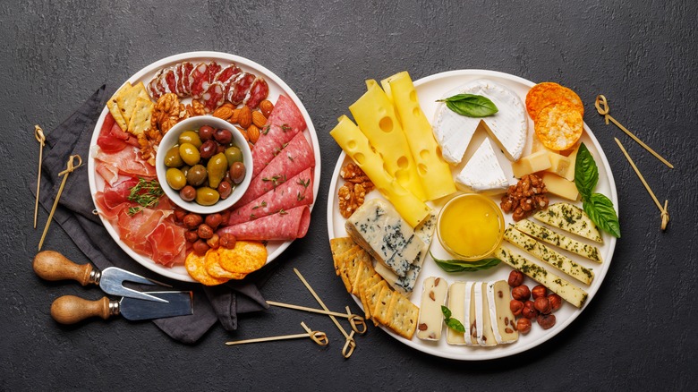 Selection of olives, nuts, various cheeses and meats on plates for antipasto spread