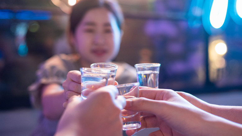 Four people raising a toast with soju