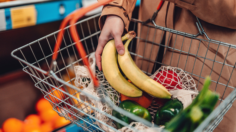 Adding a few bananas to vegetables in a shopping basket