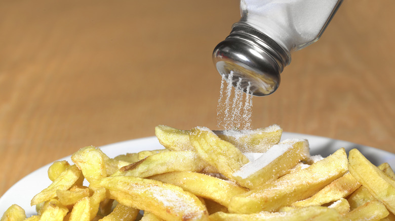 Table salt being poured on fries