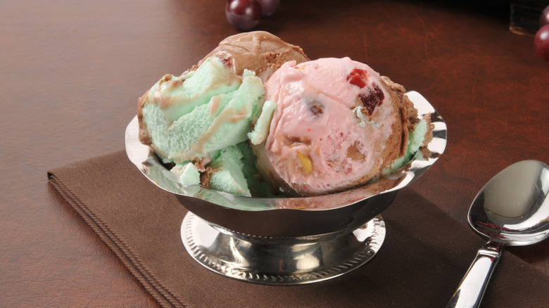 A silver dish of spumoni with chocolate, cherry, and pistachio ice cream studded with fruit and nuts.