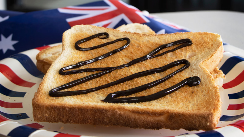 Toast with swirl of Vegemite with Australia flag in background.