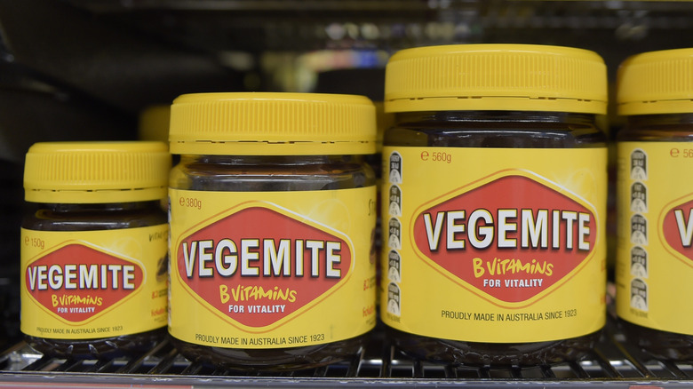 Yellow and red jars of Vegemite on a store shelf. 