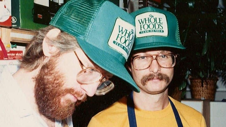 John Mackey and colleague David Matthis wearing green Whole Foods team member caps