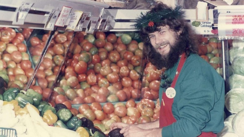 A Whole Foods Market employee standing in front of a display of tomatoes and peppers