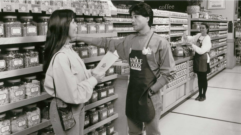 A black and white image showing a woman talking to a Whole Foods Market employee