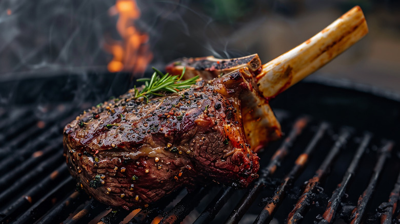 A bone-in steak with seasonings and herbs on a smoky grill