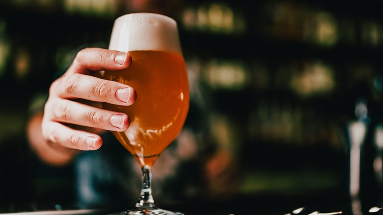 bartender serving a farmhouse ale in a fluted glass