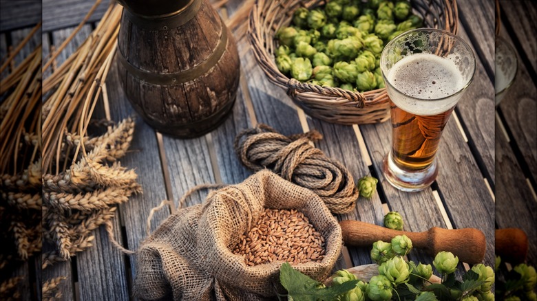 beer ingredients and a pint of beer on a rustic wooden table