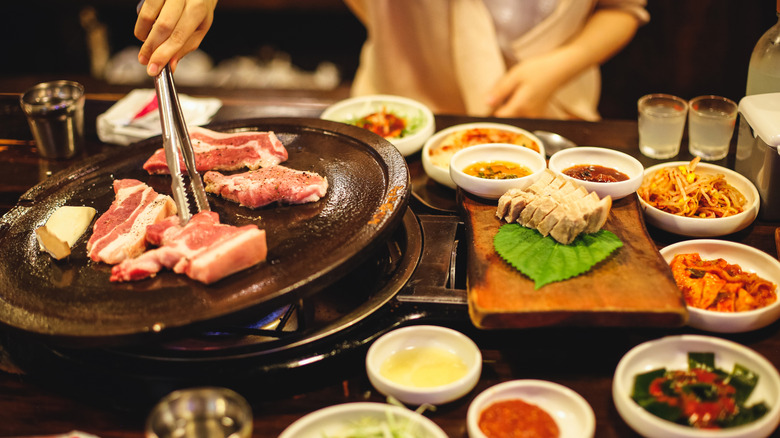 Chef preparing Korean barbecue food, closeup on hands and many ingredients.