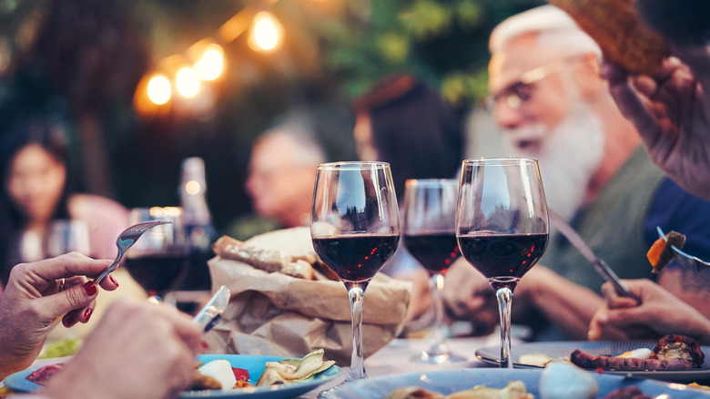 outdoor dinner party where people are eating and drinking red wine