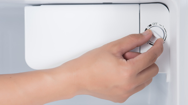 hand adjusting refrigerator temperature dial