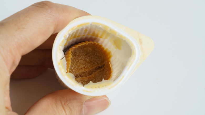 Closeup of hand holding coffee creamer cup with solidified coffee creamer