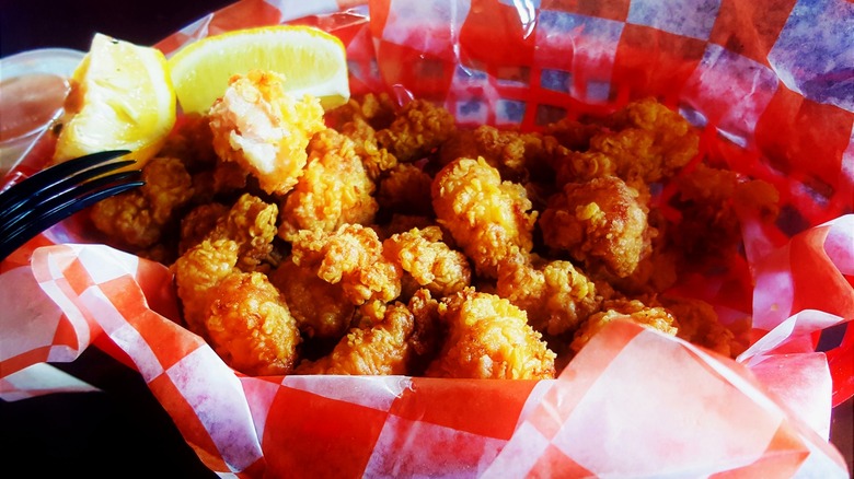 Fried alligator bites in paper lined serving basket with lemon wedges