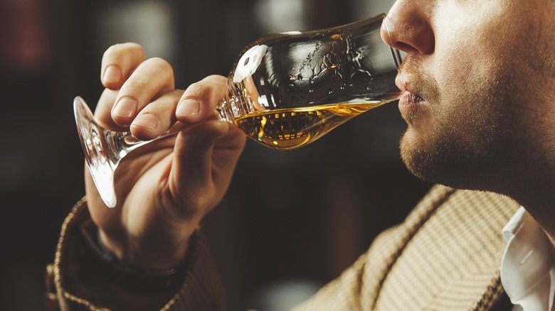 Man tasting whiskey from glass